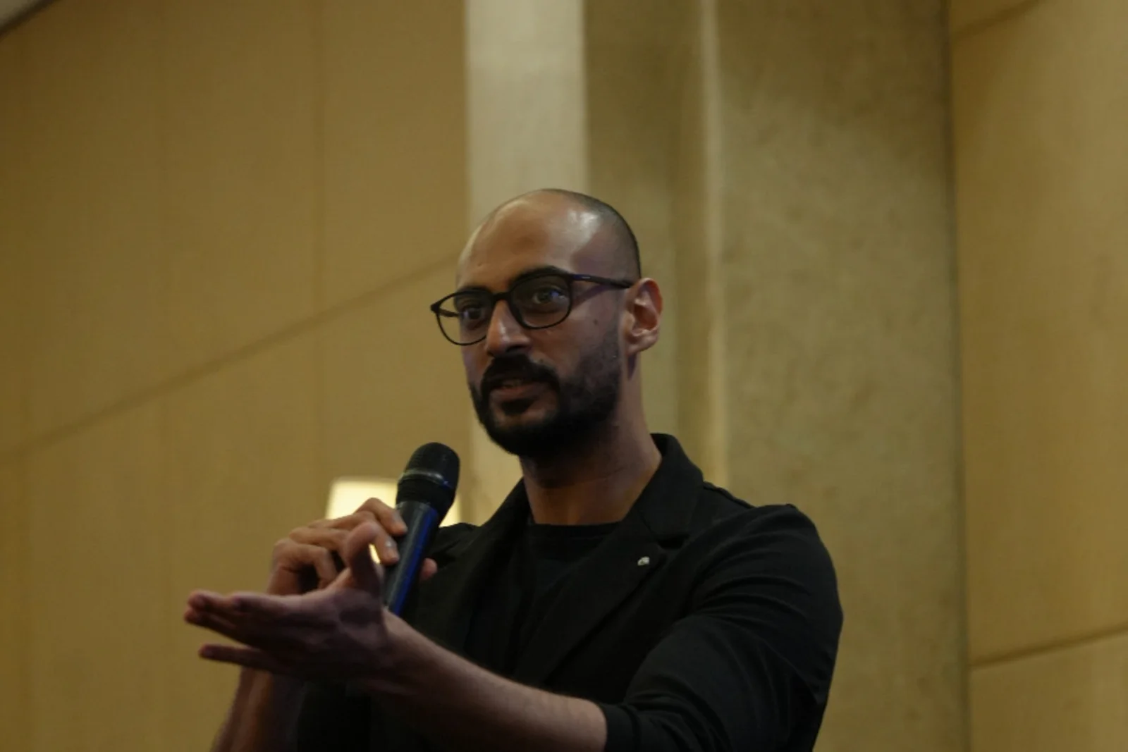 Akram Ahmed speaking into a handheld microphone during Orfloat's presentation
