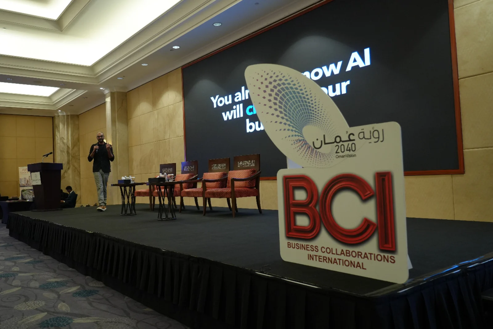 Akram Ahmed presenting Orfloat's AI work beside BCI and Oman Vision 2040 event signage