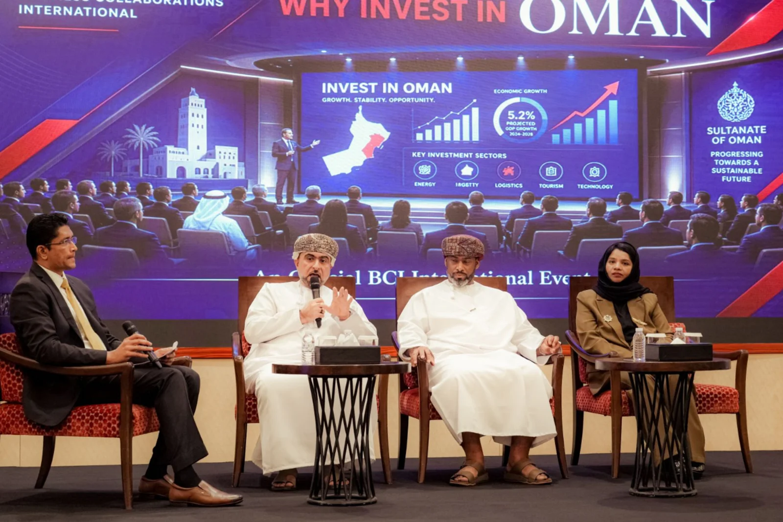 Four panel members seated onstage for the Why Invest in Oman? discussion
